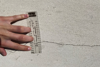 Mesure d'une fissure sur la façade du Roy avec une règle transparente.