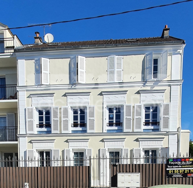 Façade du Roy d'un bâtiment avec volets blancs et balcons.