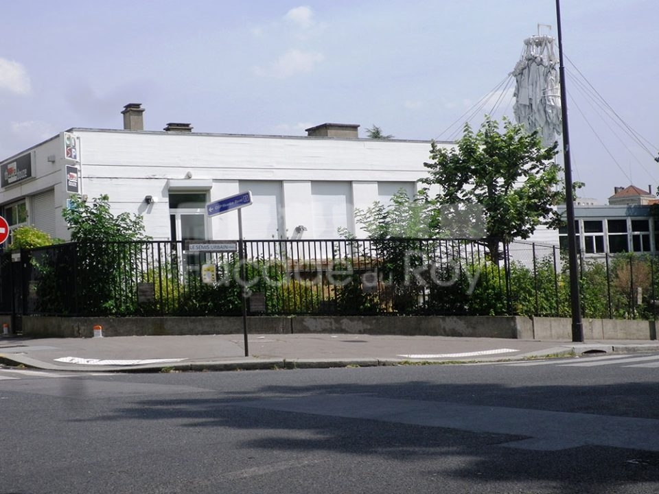 Façade du Roy avec végétation et panneau de direction visible.