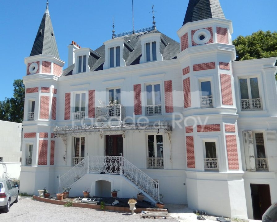 Façade du Roy avec détails architecturaux et balcon en fer forgé.